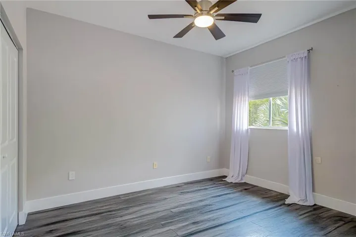 Empty room with wood finished floors, ceiling fan, and baseboards
