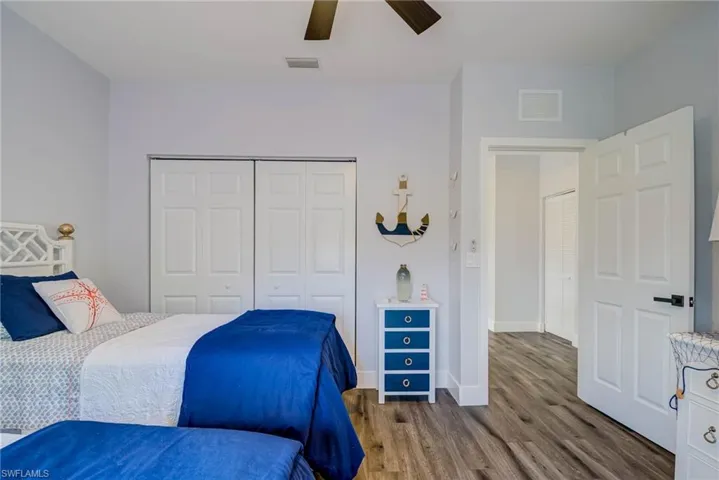 Bedroom with wood finished floors, a closet, ceiling fan, baseboards, and visible vents