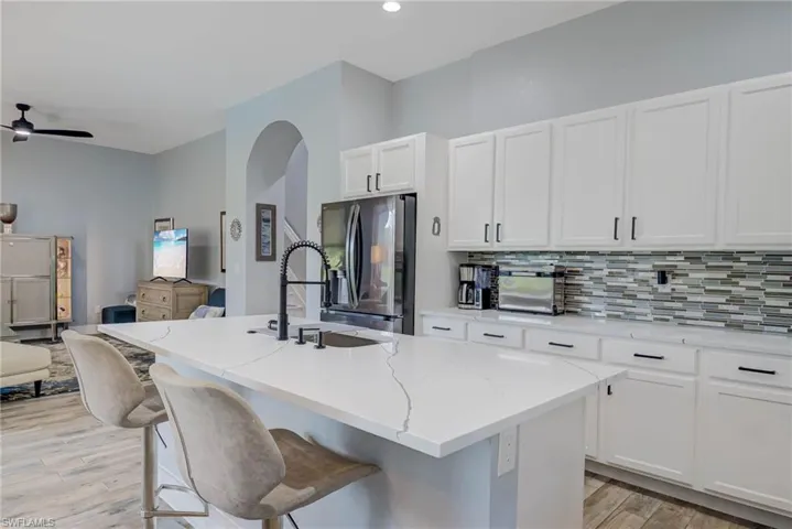 Kitchen with white cabinets, a sink, freestanding refrigerator, light stone countertops, and backsplash