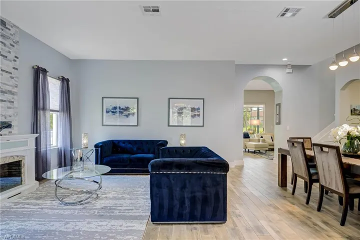 Living area featuring arched walkways, visible vents, and wood finished floors