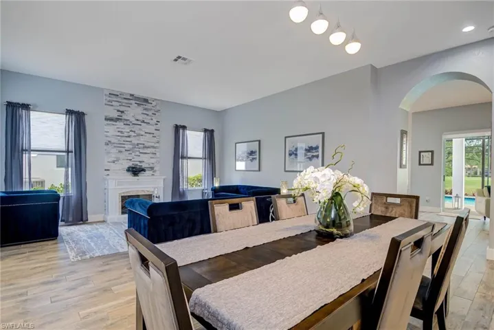 Dining area featuring a tiled fireplace, baseboards, arched walkways, and light wood-style floors