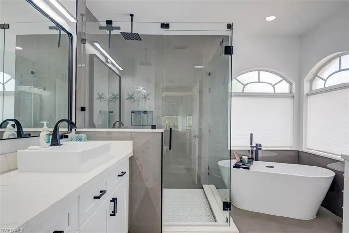 Bathroom featuring recessed lighting, tile patterned flooring, a freestanding tub, vanity, and a stall shower