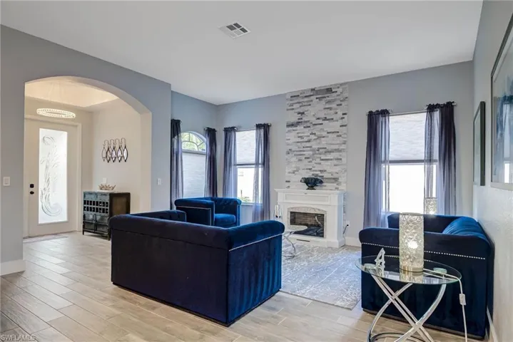 Living room with visible vents, arched walkways, light wood-type flooring, and a fireplace