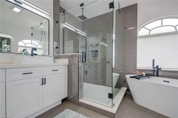 Bathroom with a freestanding tub, vanity, tile patterned flooring, and a stall shower