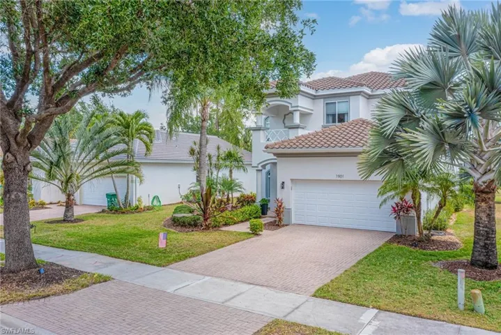 View of front of home with a tile roof, a front yard, an attached garage, decorative driveway, and stucco siding