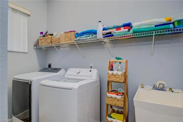 Washroom featuring separate washer and dryer, laundry area, and a sink