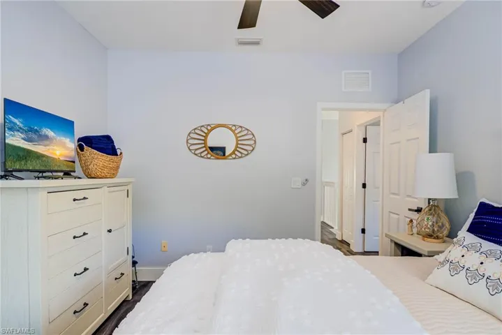 Bedroom with dark wood-type flooring, visible vents, ceiling fan, and baseboards