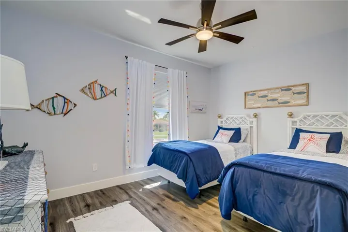 Bedroom featuring baseboards, wood finished floors, and a ceiling fan