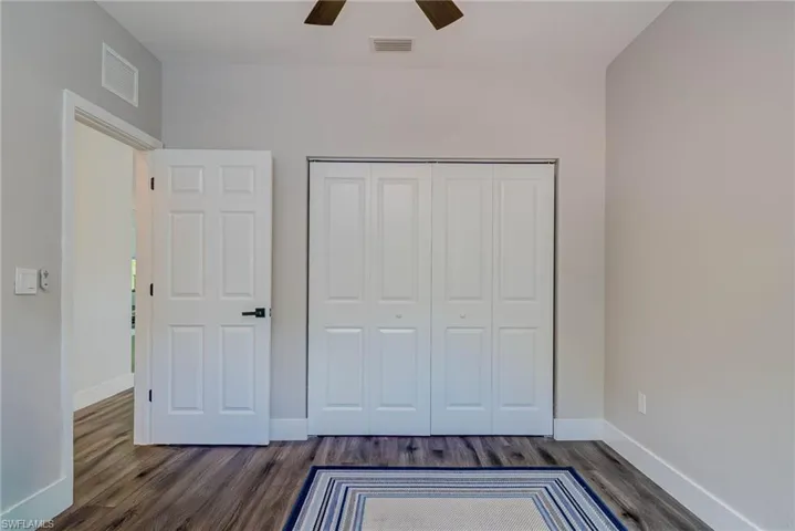 Unfurnished bedroom with dark wood finished floors, visible vents, and a closet