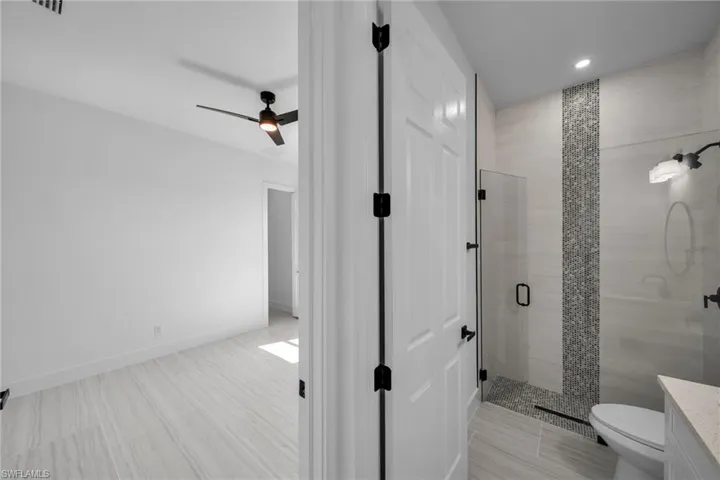 Bathroom featuring a stall shower, recessed lighting, toilet, ceiling fan, and vanity