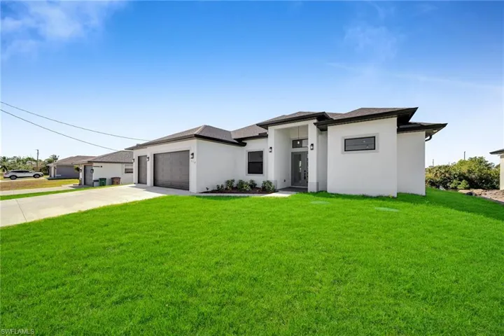 Prairie-style house featuring concrete driveway, a front yard, stucco siding, and an attached garage
