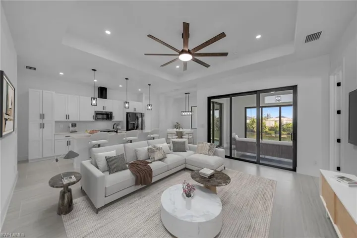 Living area with a tray ceiling, visible vents, and recessed lighting