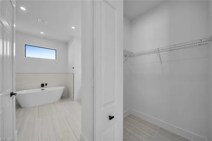 Full bath featuring a walk in closet, a freestanding bath, visible vents, baseboards, and recessed lighting