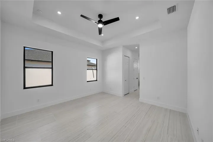 Spare room with a tray ceiling, a ceiling fan, visible vents, and recessed lighting