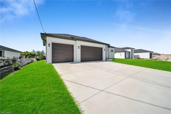 View of front of house with fence, an attached garage, concrete driveway, stucco siding, and a front lawn