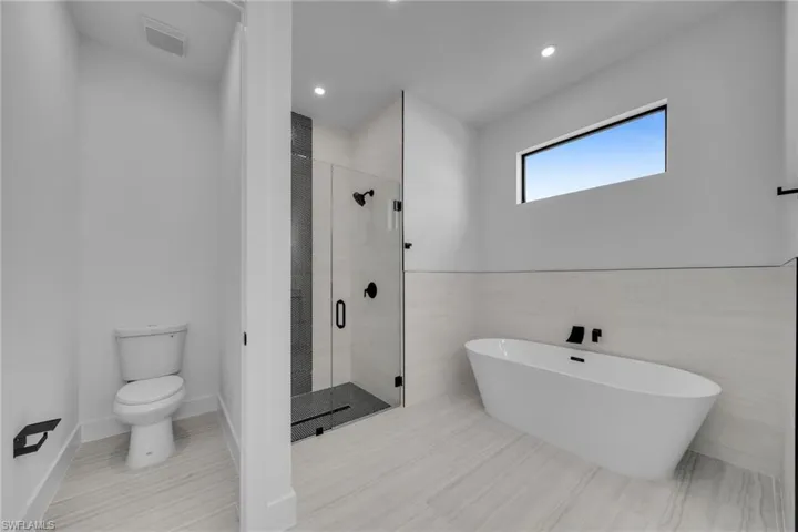 Bathroom with a stall shower, recessed lighting, toilet, visible vents, and a freestanding bath