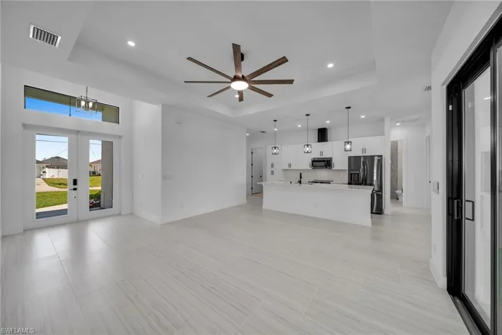 Unfurnished living room with a tray ceiling, a sink, visible vents, and recessed lighting