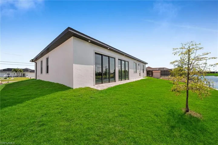 Back of property with a lawn and stucco siding