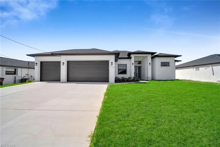 Prairie-style home with concrete driveway, a garage, stucco siding, and a front yard
