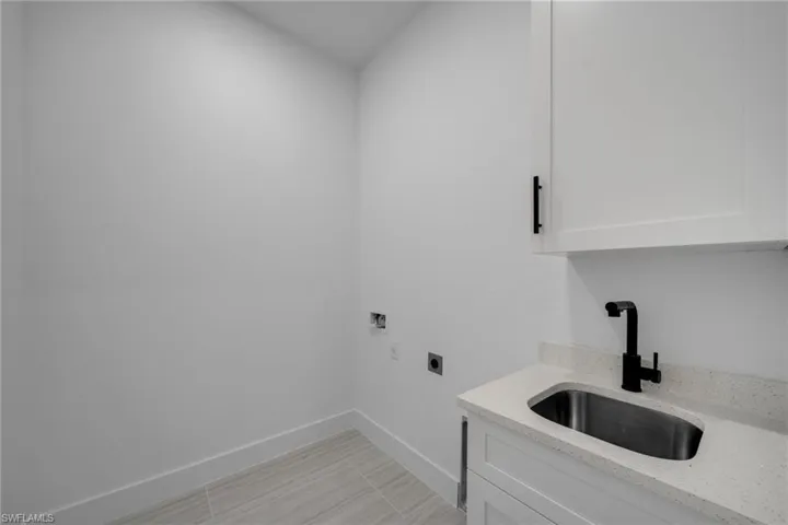 Laundry room with a sink, cabinet space, washer hookup, hookup for an electric dryer, and baseboards