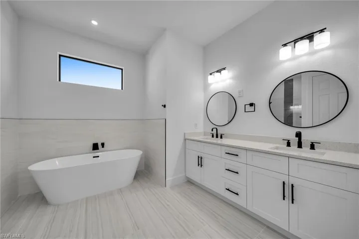 Bathroom with double vanity, a freestanding tub, and a sink