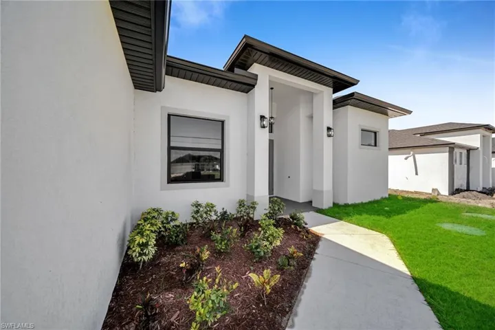 Property entrance with a yard and stucco siding