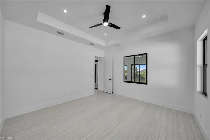 Unfurnished room featuring a ceiling fan, baseboards, a raised ceiling, and recessed lighting