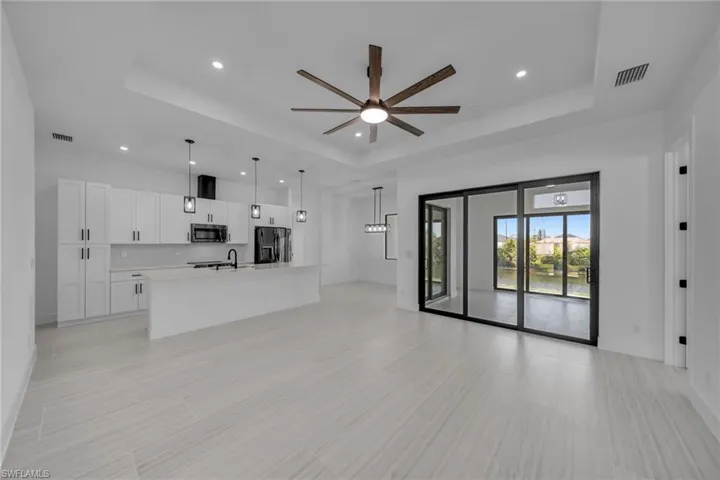 Unfurnished living room featuring visible vents, a tray ceiling, and recessed lighting