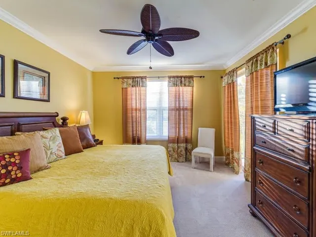 Carpeted bedroom with ornamental molding and a ceiling fan