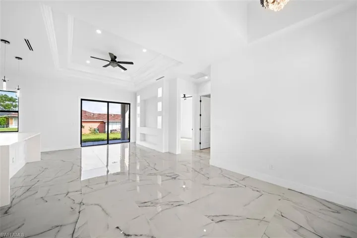Polished tile flooring, tray ceiling with recessed lighting, built-in entertainment niche, and sliding glass doors