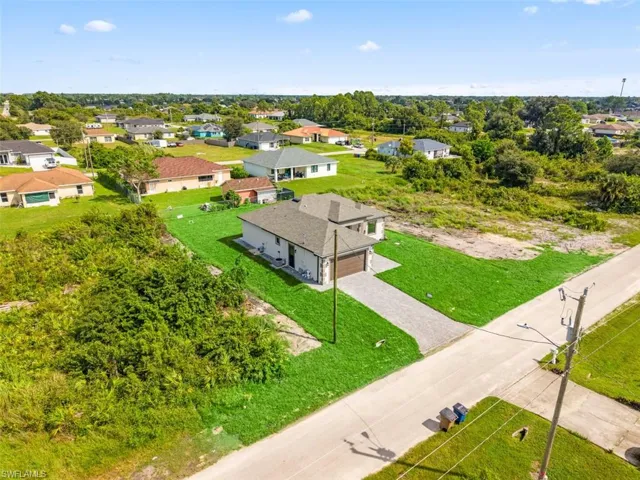 Newly constructed residence with an attached garage, a paved driveway, and established green lawn