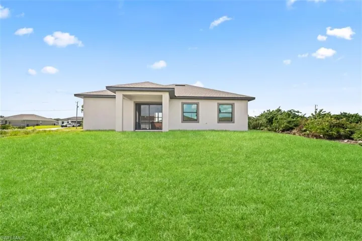 Expansive green space featuring a contemporary stucco exterior, covered patio, and dual-pane windows