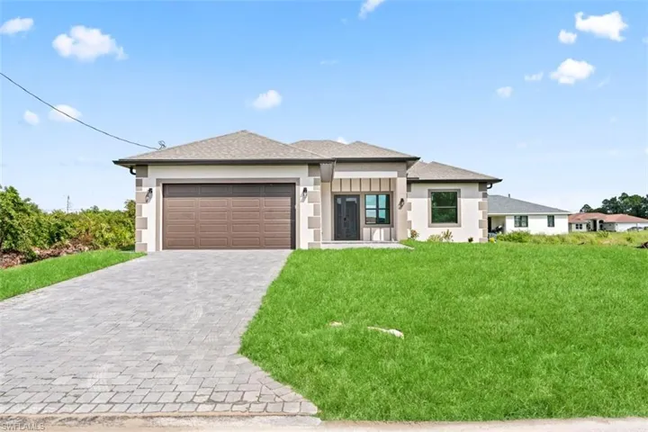 Contemporary exterior with a neutral stucco finish, stone accents, a paver driveway, a two-car garage, and a tiled roof