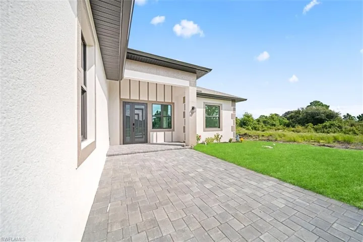 Stucco exterior with stone accent, paver patio, double-pane windows, and a glass-paneled entry door