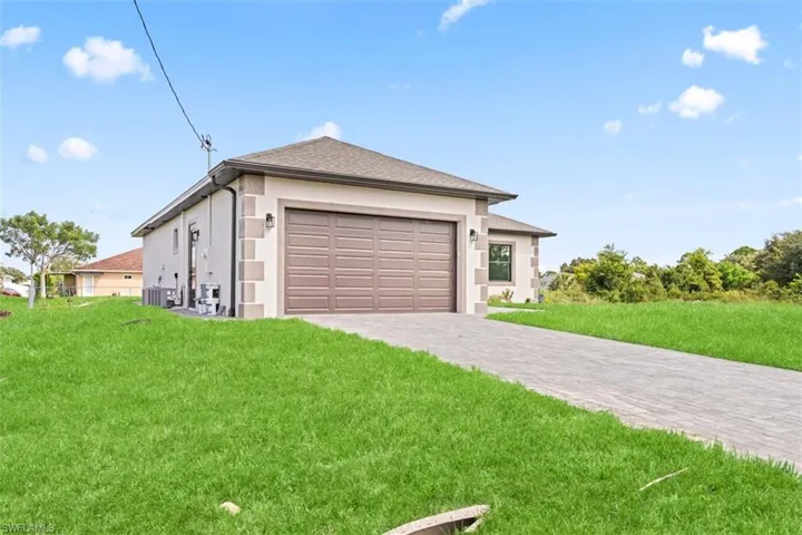 Single-story residence featuring a brown paneled garage door, decorative exterior stone accents, and a paved driveway
