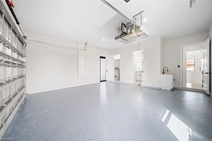 Spacious garage with an epoxy-coated floor, integrated lighting, and multiple interior access doors