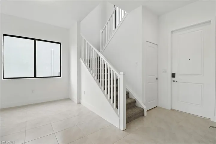 Foyer featuring stairway and light tile patterned floors