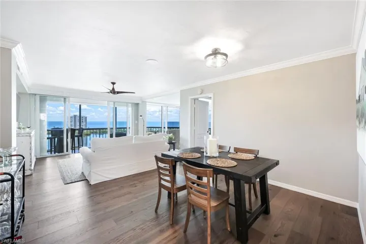 Dining area featuring ornamental molding, a water view, ceiling fan, and dark wood-type flooring