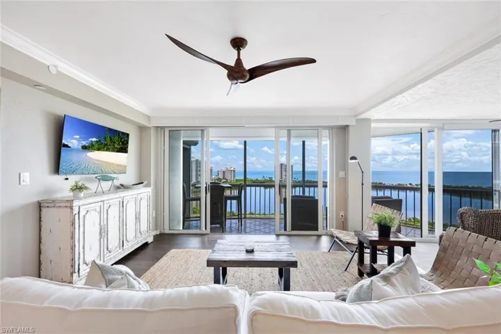 Living room featuring a water view, ceiling fan, expansive windows, wood-type flooring, and ornamental molding