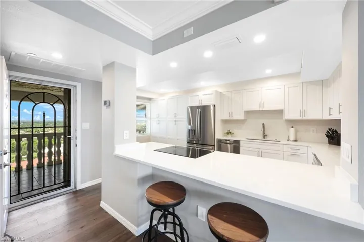 Kitchen with a breakfast bar area, stainless steel appliances, sink, kitchen peninsula, and dark wood-type flooring