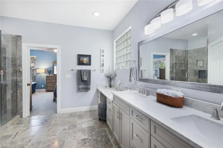 Recently remodeled en suite expansive primary bathroom with dual sinks and travertine tile throughout.