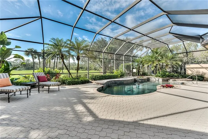 View of swimming pool with a jacuzzi, glass enclosure, and a patio
