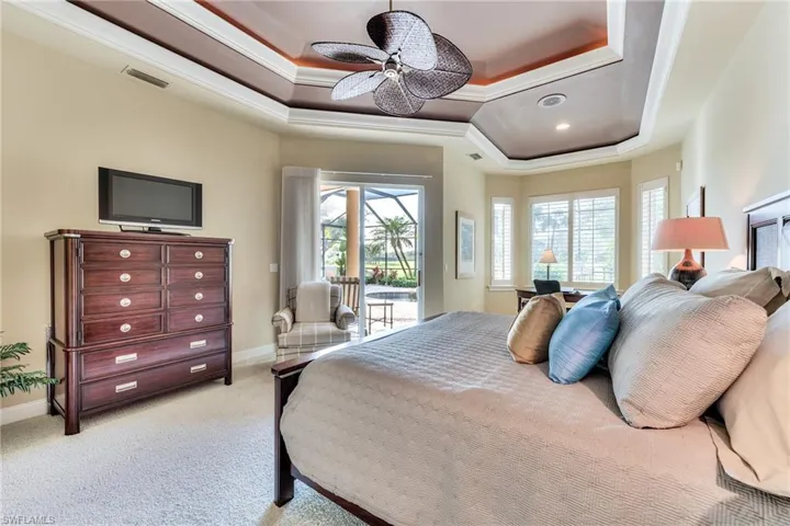 Carpeted bedroom with access to outside, ceiling fan, a tray ceiling, and ornamental molding