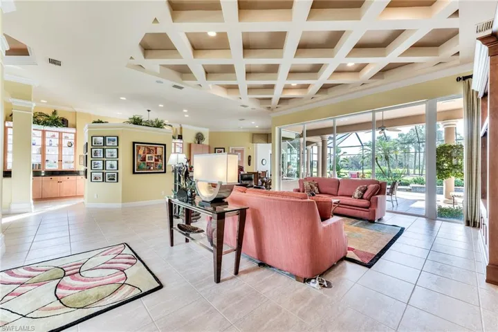Tiled living room with coffered ceiling, crown molding, and beam ceiling