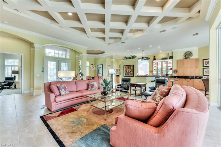 Tiled living room with a towering ceiling, french doors, decorative columns, and a healthy amount of sunlight
