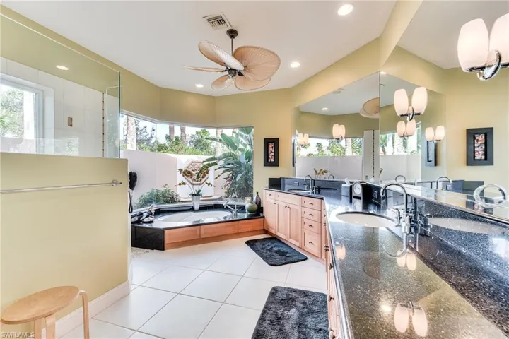 Bathroom with ceiling fan, tile patterned flooring, plus walk in shower, and vanity