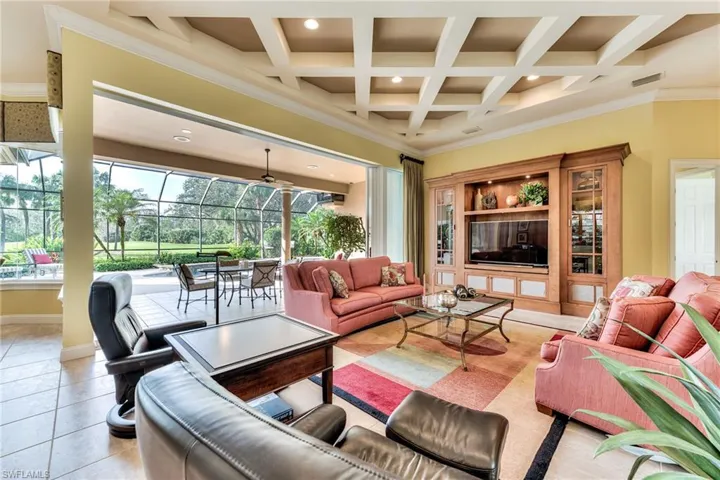 Living room with coffered ceiling, beamed ceiling, light tile patterned floors, and crown molding