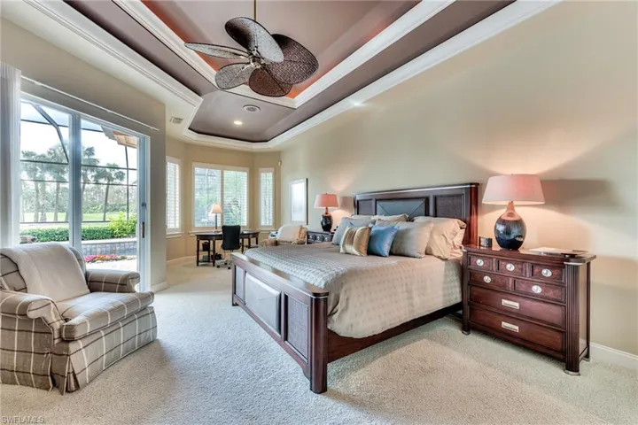 Bedroom featuring a raised ceiling, ceiling fan, crown molding, and light colored carpet
