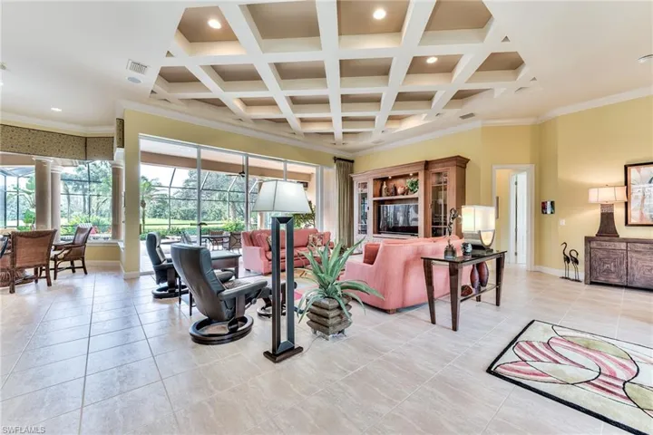 Living room featuring coffered ceiling, ornamental molding, and beam ceiling