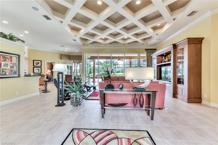 Tiled living room featuring beam ceiling, ornamental molding, and coffered ceiling